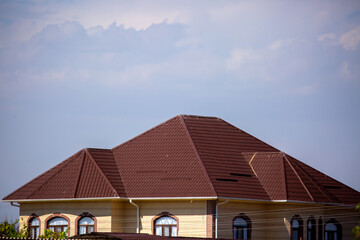 Roofs of houses from a metal profile against the sky. Roofing. Metal tiles on the roofs of houses.