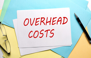 OVERHEAD COSTS text on paper sheet with chart,color paper and calculator
