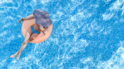 Beautiful woman in hat in swimming pool aerial top view from above, young girl in bikini relaxes...