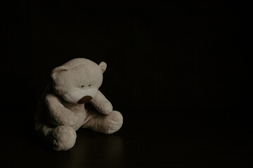 Teddy bear is sitting in the dark. Child abuse and punishment concept. Lonely concept, international missing children's day