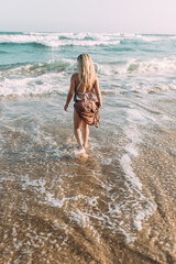 Junge blonde Frau mit langen Haaren am Strand im Wasser am Meer