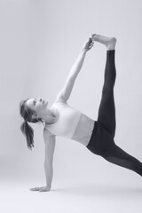 Black and white serie of photos of young fit woman practising yoga. Studio shot on white background.