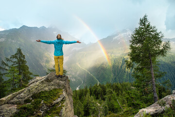 Woman standing with arms outstretched out in front of a beautiful scenery with mountains and...