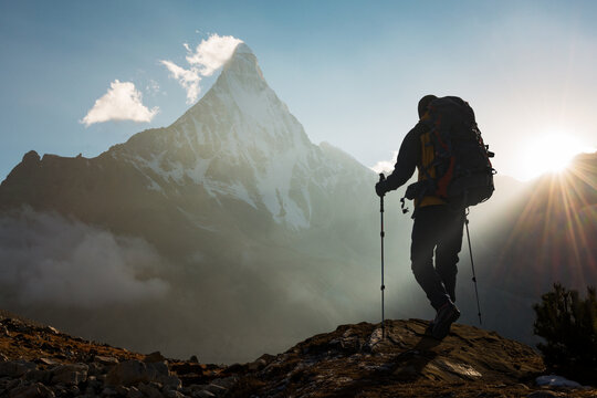 Mountain Man with backpack hiking in the mountains at sunset