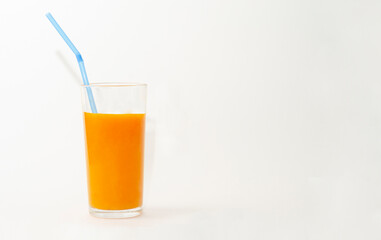 a glass of pumpkin juice with blue straw on white background