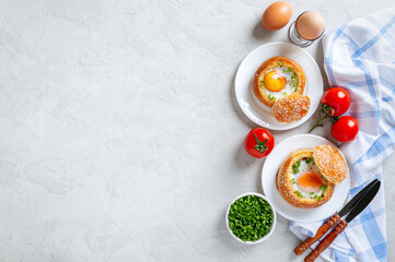 Baked buns stuffed with eggs and bacon on plates on a light background. Breakfast eggs. Top view with copy space.
