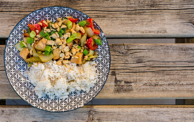 Vegan Asian dish with Tofu, vegetables and rice on weathered wooden table