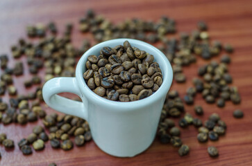 coffee beans in a white cup on brown wood background