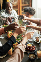 Close-up of family toasting with glasses of drinks while sitting at dining table during dinner