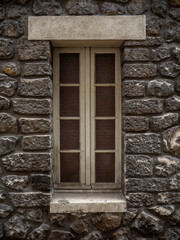 Fototapeta na wymiar imagen de una ventana entre una fachada de piedra gris oscuro y las juntas de cemento 