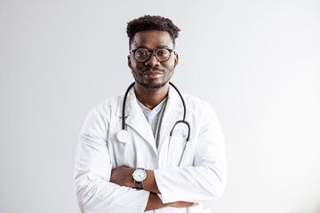 Portrait Of African American Male Doctor Wearing White Coat Standing In Hospital Corridor. Portrait of confident mature black doctor looking at camera. Smiling african american doctor with stethoscope