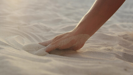 Cropped shot of female hand touching sand on beach - obrazy, fototapety, plakaty