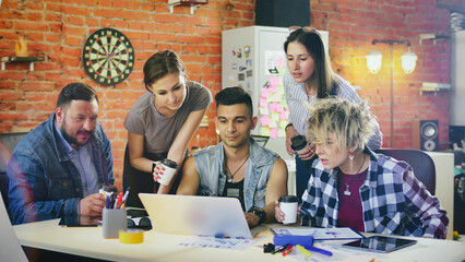 Group Creative team with takeaway coffee discuss ideas using laptop in studio