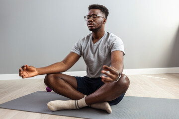 African yoga teacher meditating. Man practicing yoga and meditation at home. A series of yoga...