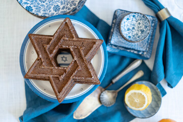 Flatlay shoot Food for Independence Day of Israel celebration, cake and table setting, jewish symbol centerpieces, white and blue. Star of David shaped pie. Israeli flag decoration