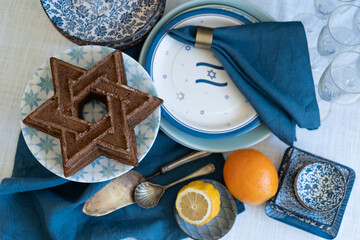 Flatlay shoot Food for Independence Day of Israel celebration, cake and table setting, jewish symbol centerpieces, white and blue. Star of David shaped pie. Israeli flag decoration