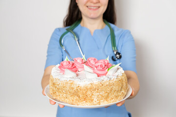 The doctor or nurse holds a large birthday cake, congratulations on the day of the doctor or nurse