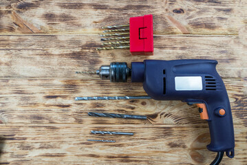 drill and a set of drills on a wooden background.