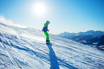 Snowboarder boy go downhill on snowboard at alpine ski slope
