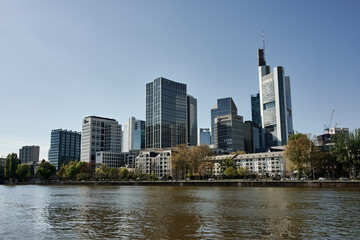 Fototapeta na wymiar River Main and skyline in Frankfurt, Hesse, Germany. Office buildings and skyscrapers behind the water. Urban architecture.