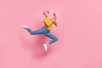 Fototapeta na wymiar Full size photo of jumping cheerful girl browsing in telephone 5g connection isolated on pink color background