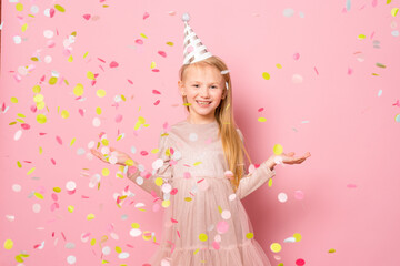 Obraz na płótnie Canvas little happy young girl making party with confetti standing isolated over pink background.