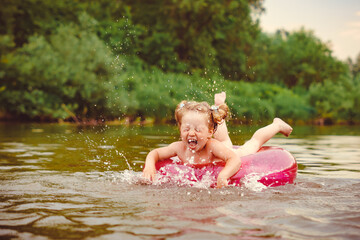 a child swims in the river in an inflatable circle