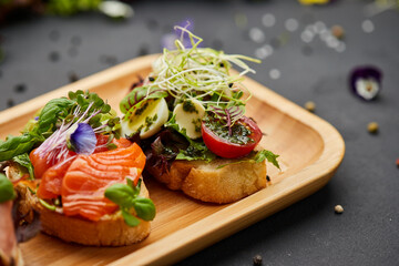Assorted bruschetta set with salmon, parma and pesto souce. Italian antipasti snacks. Variety mix of small sandwiches on dark background. Photo for restaurant menu