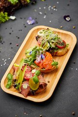 Assorted bruschetta set with salmon, parma and pesto souce. Italian antipasti snacks. Variety mix of small sandwiches on dark background. Photo for restaurant menu