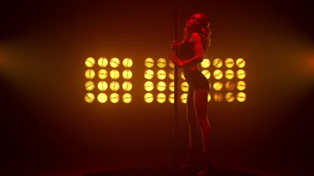 Hot blonde showing erotic dance in strip club. Sexy woman performing poledance.