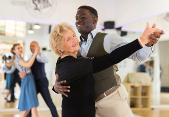 Obraz premium Elderly woman learning ballroom dancing in pair in dance studio