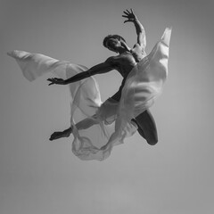 Flight. Black and white portrait of graceful muscled male ballet dancer dancing with fabric, cloth...