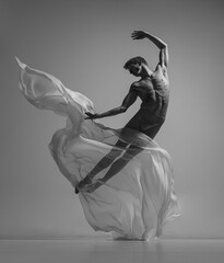 Hope. Black and white portrait of graceful muscled male ballet dancer dancing with fabric, cloth...