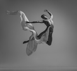 Desire. Black and white portrait of graceful muscled male ballet dancer dancing with fabric, cloth...