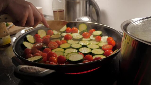 Tomatoes and zucchini frying in pan