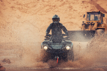Quad rider go fast at the sands dunes through water. Quad Bike driver ride at the desert with a...