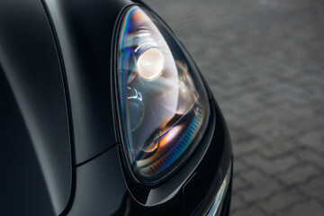 Headlight of modern luxury car close up. Front side of clean black SUV car