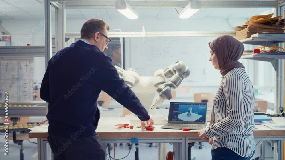 Poster Chief Male Engineer Chatting with Arabic Female Computer Science Specialist While Gathering at the Table with Robotic Hand. Promising Computer Scientist Collaboration Concept. Medium Shot
