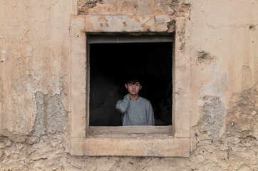 Portrait of teenage Asian boy behind window frame of an abandoned building