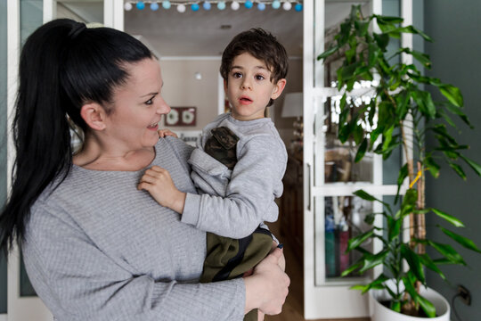 Autistic boy with a lost look in the arms of his smiling mother