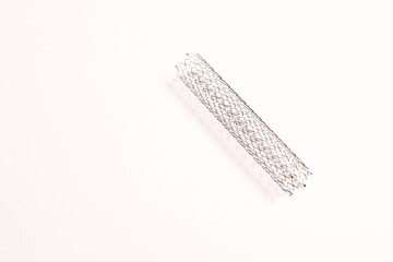A stent used in angioplasty procedure placed on a white surface.