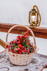 A basket with red decor and a lantern in the snow outside