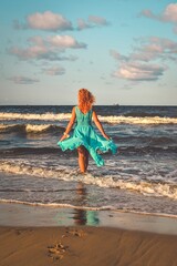 Beautiful blonde haired woman on the beach. Girl in a blue dress at the Polish seaside.