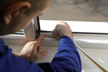 Construction worker putting sealing foam tape on window indoors, closeup