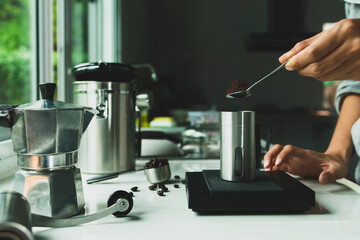 powder coffee on a stainless spoon with hand people pour Roasted coffee for espresso coffee into the cup with equipment tool brewing Italian Moka pot, coffee at kitchen home. preparation drink