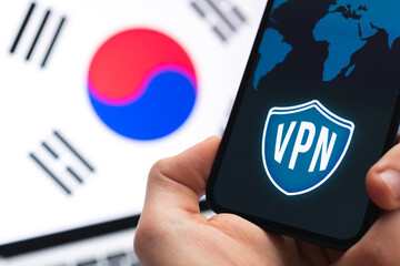 VPN in South Korea. Secure and safe internet concept. Privacy. Hand with mobile phone and VPN application. Flag and laptop on the background