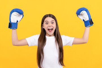 amazed child in boxing gloves on yellow background