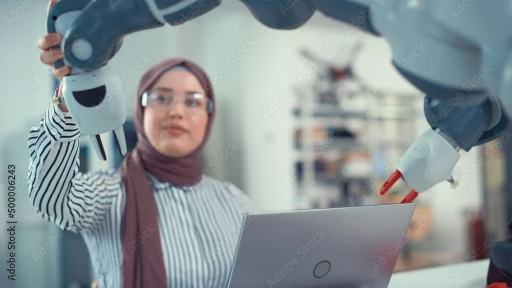 Aufkleber Middle Eastern Engineer in Hijab Undergo an In-depth Analysis of the Robot Arm and Programming at Laptop at Modern Office. Optimisation of Autonomous Manufacturing Facility That Creates Great Product