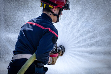 jeune pompier Français qui tient une lance à incendie lors d'un exercice