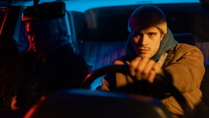 Beautiful Young Couple Sitting in Awkward Silence in a Vintage Looking Car with Neon Lights Surrounding Them and a Street Light Hitting the Man's Face in an Artistic Way.